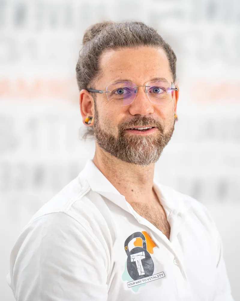 Andy Hoffmann in seiner Praxis in Lich, ruhig lächelnd, im Polo mit dem BodyMind-Logo.